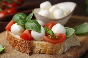Tasty sandwich with mozzarella cheese, tomatoes and basil on table, closeup