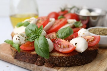 Tasty sandwiches with mozzarella cheese, tomatoes, basil and spices on light table, closeup