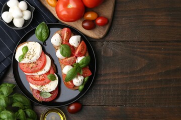 Tasty sandwiches with mozzarella cheese, tomatoes, basil and spices on wooden table, flat lay. Space for text