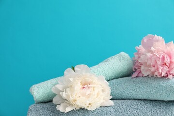 Soft towels and peony flowers on light blue background, closeup