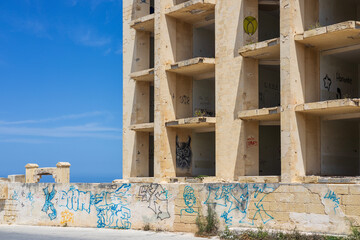 Marsaskala, Malta - 05.12.2025: An abandoned and forgotten empty shell of a hotel resort covered in...