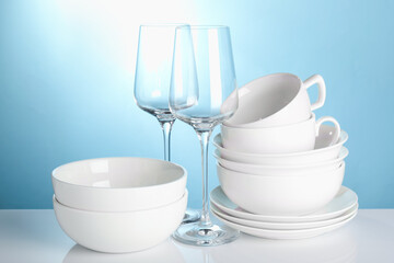 Different clean dishes on white table against light blue background