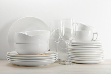 Different clean dishware on light wooden table near white wall