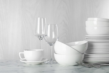 Different clean dishware on white marble table indoors