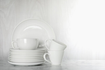 Different clean dishware on white marble table indoors, space for text