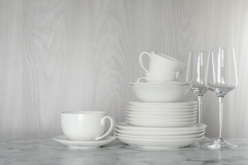 Different clean dishware on white marble table indoors, space for text