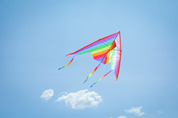 Colorful kite flying in blue sky, low angle view