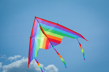 Colorful kite flying in blue sky, bottom view