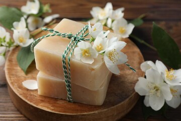 Soap bars and jasmine flowers on wooden table, closeup