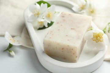 Soap bar and jasmine flowers on white table, closeup