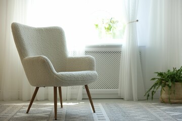 Comfortable white armchair near window indoors, space for text. Interior design