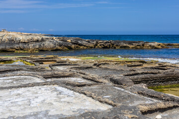 Old salt pans at the coast of Malta with a distant view of a city, Marsaskala, Maltese Islands.