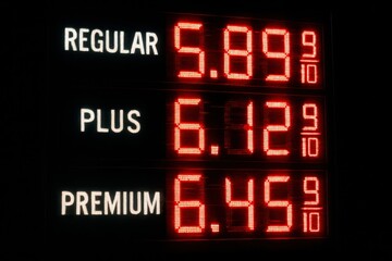 Illuminated gas price sign displaying regular, plus, and premium gasoline prices, all exceeding $5.00 per gallon during a period of inflation.