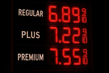 Fototapeta premium A close-up of a gas station price display showing exorbitant fuel costs, illuminated by bright red LED numbers against a stark black background, a sign of inflation.