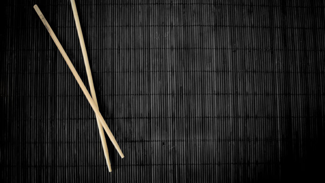 Minimalist Top View of Wooden Chopsticks on Black Bamboo Mat Background