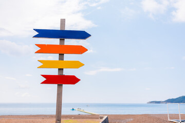 Wooden beach signpost with arrows on seaside promenade, copy space. Summer vacation, coastal...