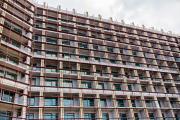 Modern glass building under construction with full scaffolding. Urban development, contemporary architecture, and city infrastructure progress.