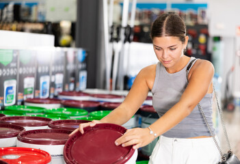Girl examine bucket of paint and buys, collect necessary supplies in store according to list for...