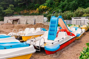 Colorful pedal boats on shore. Summer recreation, water sports, and tourism infrastructure close-up