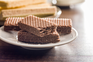 Sweet wafers filled with chocolate cream on plate  on wooden table.