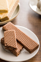 Sweet wafers filled with chocolate cream on plate  on wooden table.
