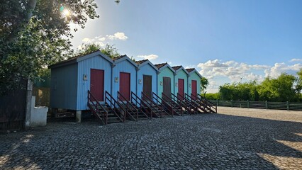 Colorful Row of Elevated Wooden Huts with Trees – Scenic Rural View