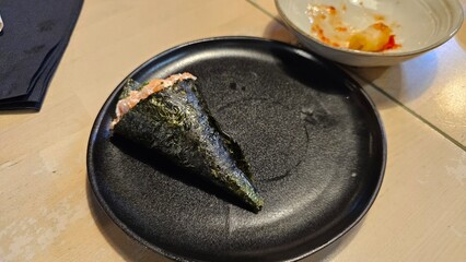 Hand Roll (Temaki) with Salmon and Seaweed on Black Plate