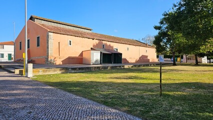 Historic salmon-colored building with tile roof and cobblestone pavement
