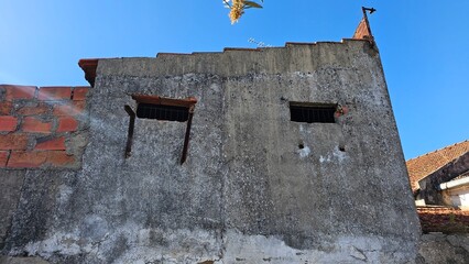 Old Abandoned Building with Two Barred Windows and Exposed Brick
