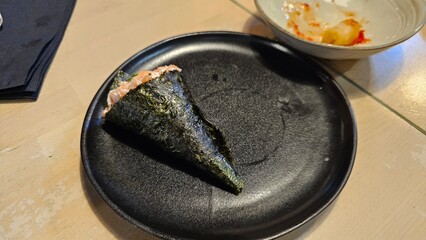 Salmon temaki served on black plate in Japanese restaurant