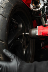 Motorcycle Rear Wheel Removal. Mechanic uses high-torque impact wrench to remove the rear wheel of...