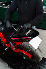 Motorcycle seat removal is essential for inspecting the electrical system. Technician carefully...