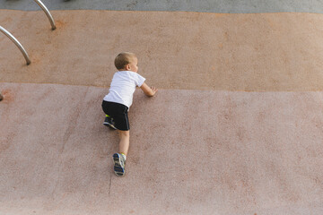 little boy climbing stone wall on playground. sport life concept