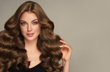 Obraz na płótnie Canvas Brunette girl with long and shiny wavy hair . Beautiful model woman with curly hairstyle . Beauty and cosmetology
