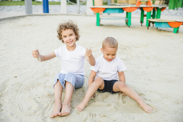 boy and girl blonde, brother and sister play in the sandbox and have fun
