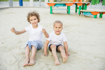 boy and girl blonde, brother and sister play in the sandbox and have fun
