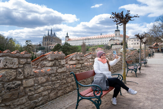 Mujer turista tom&aacute;ndose una selfie en una plaza de kutn&aacute; hora, con la Catedral de fondo