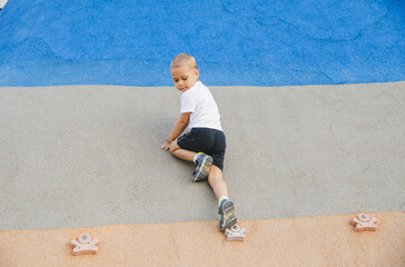 little boy climbing stone wall on playground. sport life concept