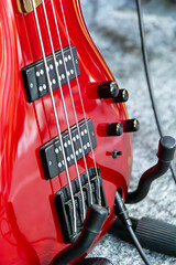 Close-up of a vibrant red electric bass guitar showcasing its details and accessories