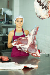 Female butcher, experienced and skilled, adeptly handles fresh meat, preparing it for customers.