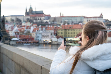 Mujer turista tomando una fotografía de las vistas de Praga, desde el Puente de Carlos