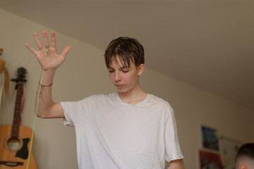 A young man, dressed in a crisp white shirt, is raising his hands enthusiastically in the air,...