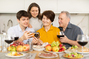 Happy family members looking through photos in light home interior during family holiday