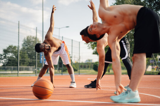 Basketball players stretching together before game outdoors