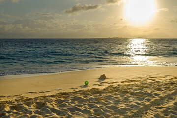 A bucket left behind from building sandcastles at sunrise in the Bahamas, and the sunlight makes the sand look golden.