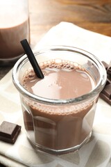 Chocolate milk in glass and ingredient on wooden table, closeup