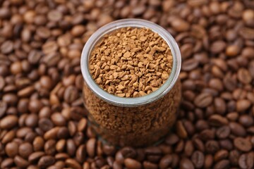 Fototapeta premium Glass jar with granulated instant coffee on beans, closeup