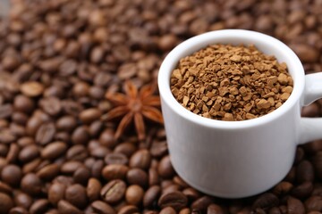Cup with granulated instant coffee and star anise on beans, closeup. Space for text