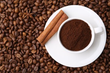 Cup with instant coffee powder and cinnamon on beans, top view. Space for text