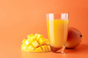 Tasty mango juice in glass and fresh fruits on orange background